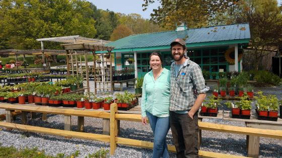 Woman and man standing in front of farm stand with plant starts