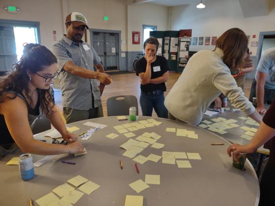 People standing at tables, talking, and sorting papers