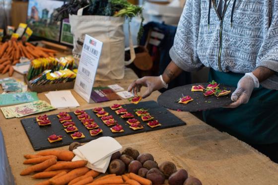 a food vendor places vegan snacks on their display table