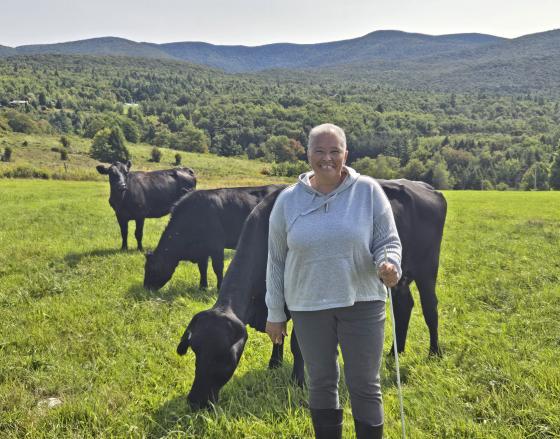 woman farmer standing with beef herd in green pasture